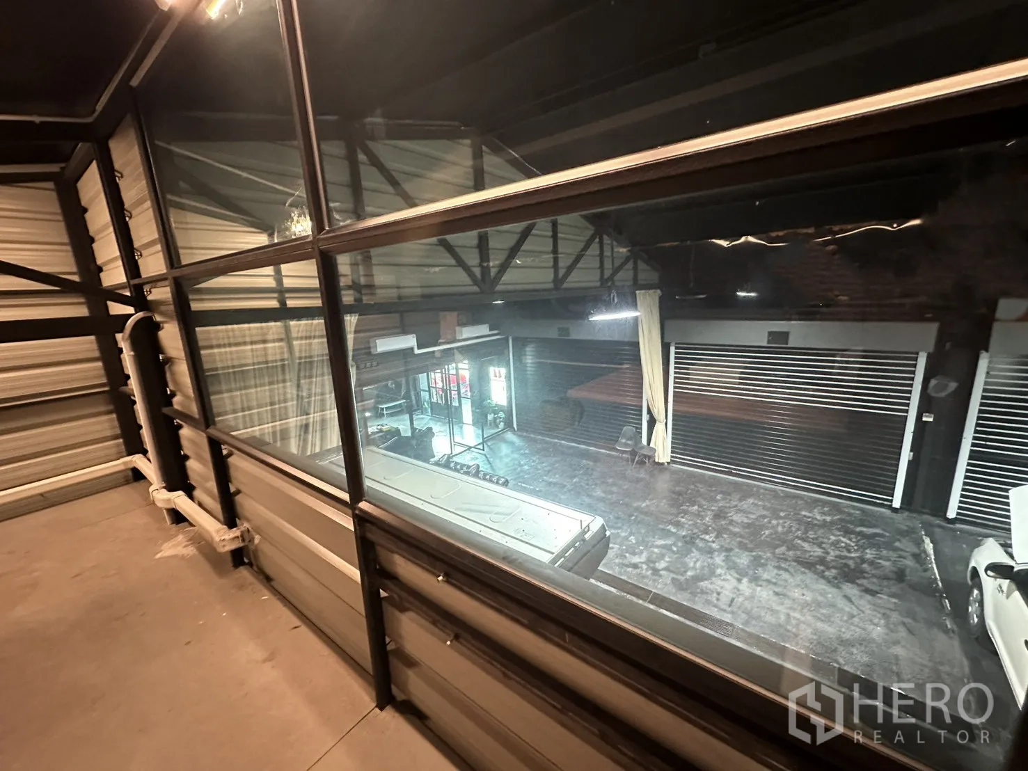 Warehouse for rent in Phra Khanong, Bangkok - View from the mezzanine through glass panels to the warehouse floor below.