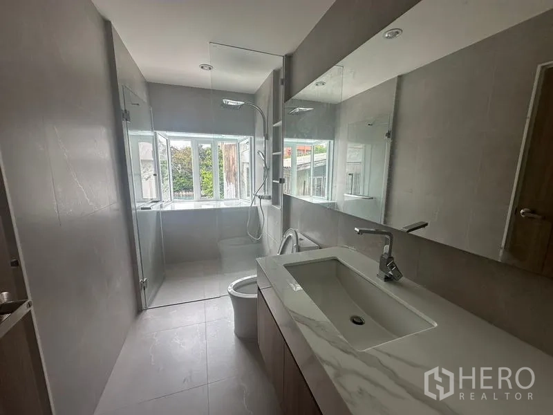 Home Office for rent in Khlong Toei, Bangkok - Bright bathroom with wide vanity, glass shower enclosure and a window bringing natural light.