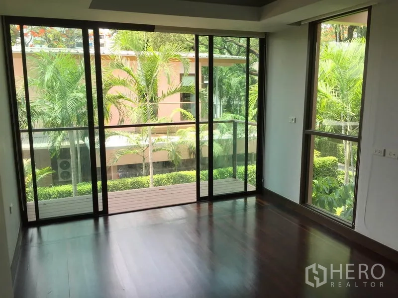 Detached House for rent in Sathon, Bangkok - Bedroom with floor-to-ceiling windows and balcony overlooking tropical greenery