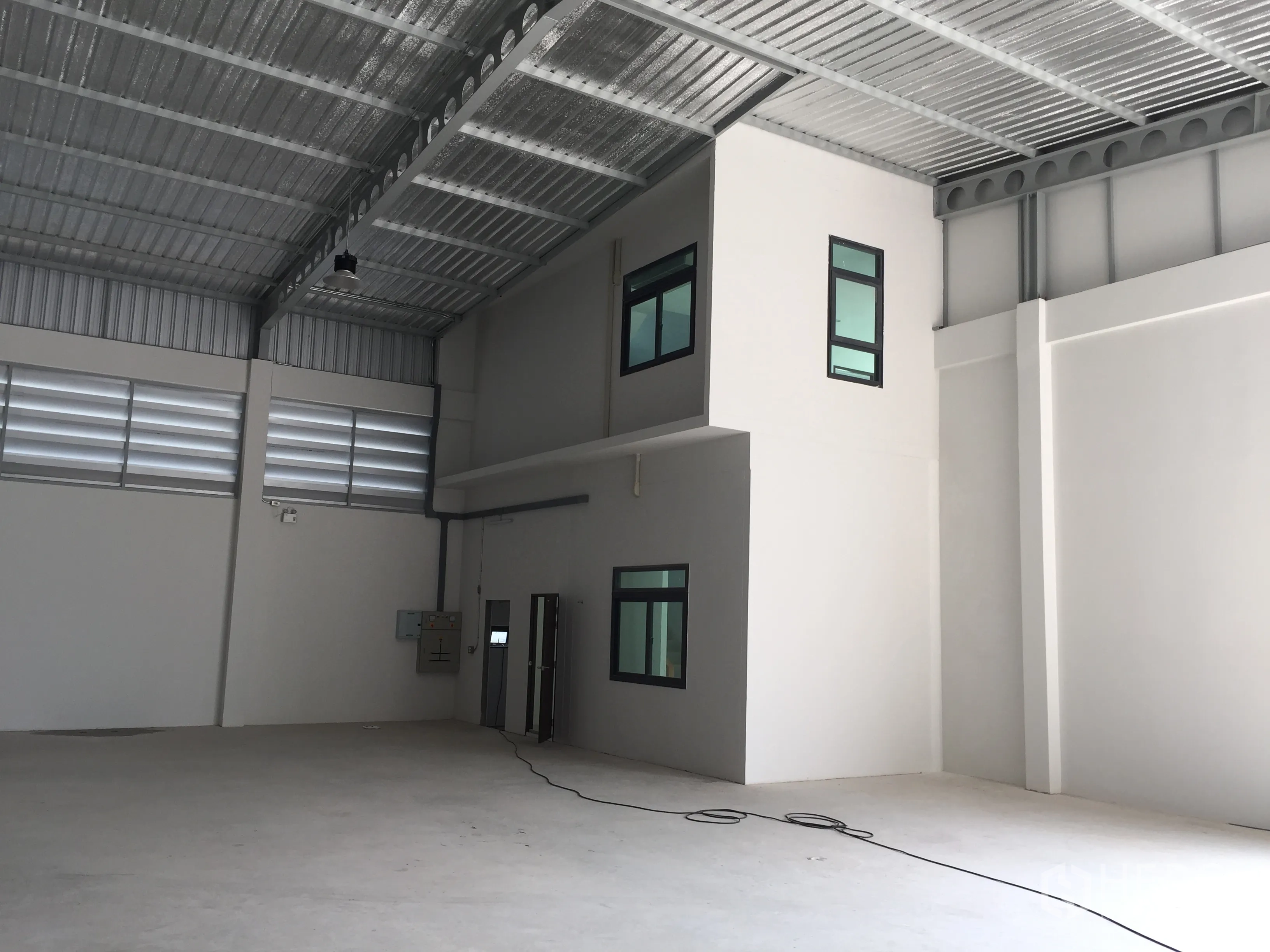 Factory for sale in Lam Luk Ka, Pathum Thani - Warehouse corner showing an internal two-level office pod and electrical panels.