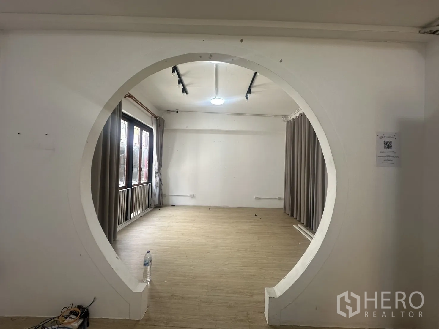 Home Office for rent in Pathum Wan, Bangkok - Feature circular doorway opening to a bright multipurpose room with curtains.
