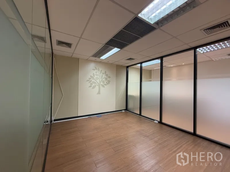 Office Space for rent - Private meeting room with frosted glass walls and tree motif, wood floor and ceiling lights.