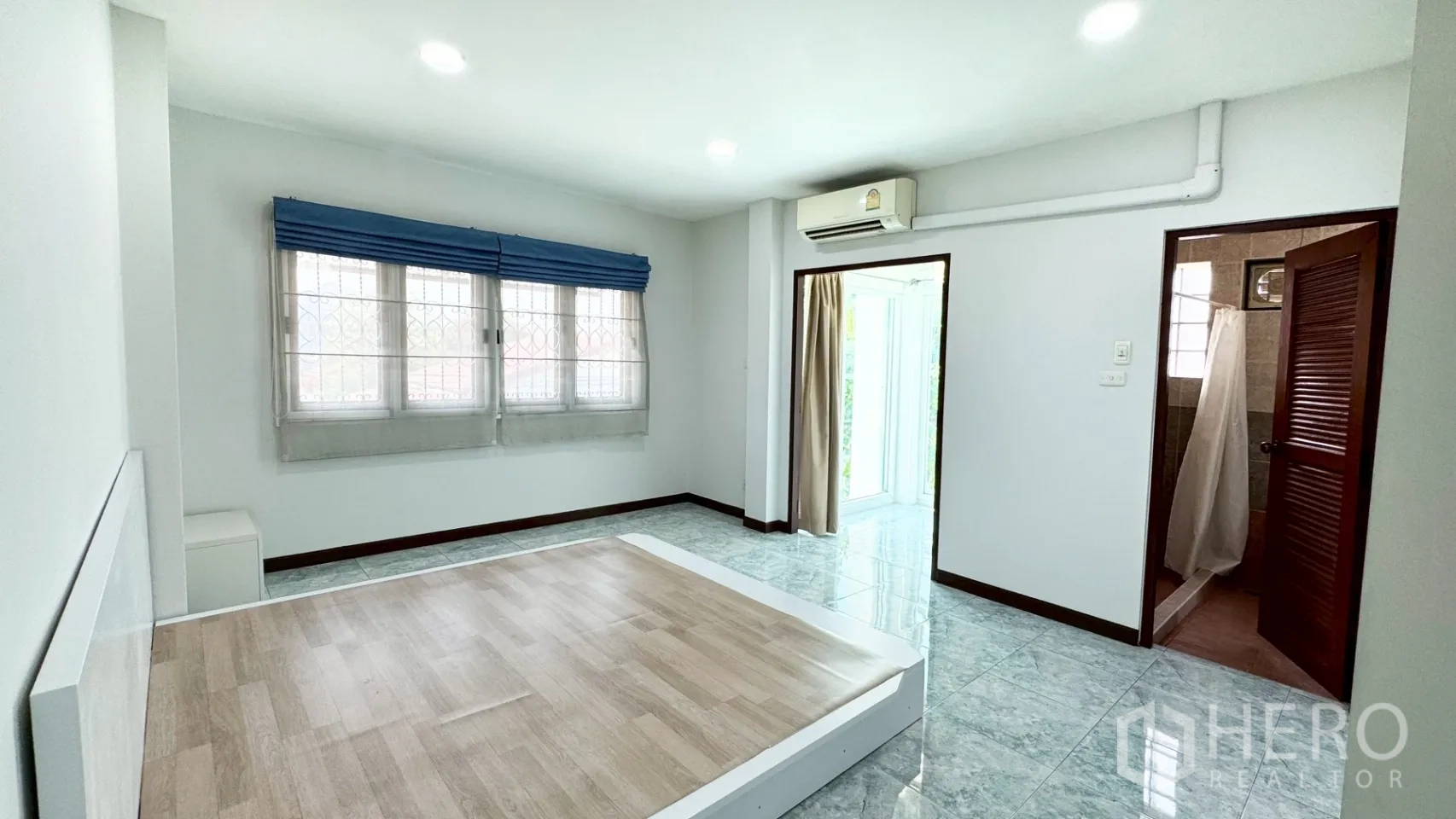 บ้านเดี่ยว for rent in Suan Luang, Bangkok - ห้องนอนพร้อมฐานเตียงบิลท์อิน ม่านสีฟ้าอ่อน และประตูเชื่อมเข้าห้องน้ำส่วนตัว