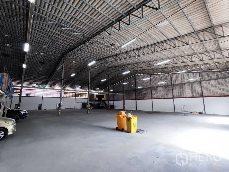 Warehouse for rent in Bang Phli, Samut Prakan - Large clear-span floor area under high roof with concrete surface and central utility bin.
