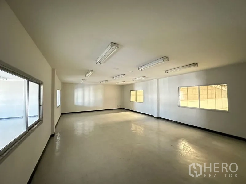 Factory for rent in Si Racha, Chon Buri - Upper office space with vinyl flooring, several windows and fluorescent light fixtures.