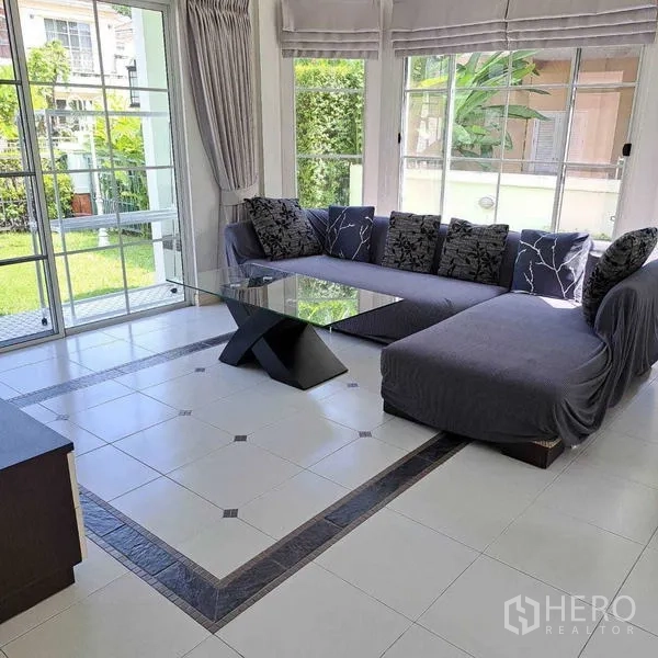 Detached House for rent in Prawet, Bangkok - Corner living area featuring an L-shaped sofa, glass coffee table and wraparound windows.