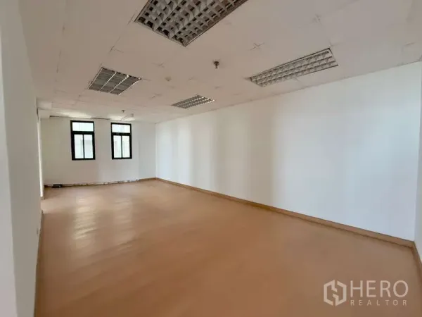 Office Space for rent in Chatuchak, Bangkok - Bright unfurnished office with wood-look floors, white walls and three black-framed windows.