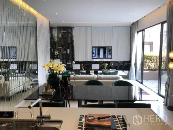 Detached House for sale in Bang Kapi, Bangkok - Open-plan Bangkok living area with mirrored wall, black dining table and floor-to-ceiling glass doors leading to a patio.