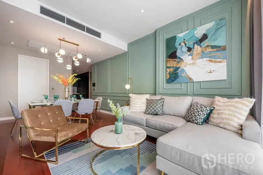 Condominium for rent or sale in Watthana, Bangkok - Bright Thonglor condo living room with sage panelled wall, sofa, marble coffee table and open dining area.