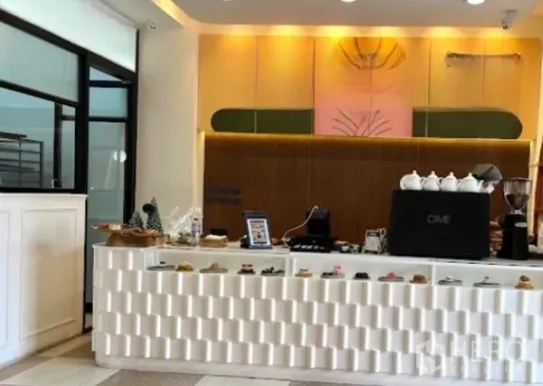 零售空间 出租在Watthana, Bangkok - 现代白色吧台，陈列糕点与咖啡机，暖色照明。