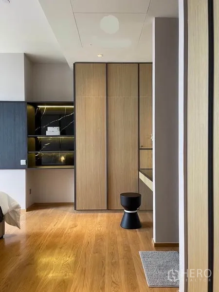 Condominium for rent in Khlong Toei, Bangkok - Walk-in wardrobe and dressing nook with wood panels, black marble shelving and a vanity.