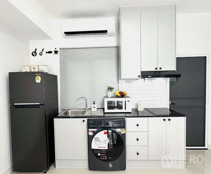 Townhouse for rent in Bang Phli, Samut Prakan - Compact white kitchen with appliances and washer-dryer combo.