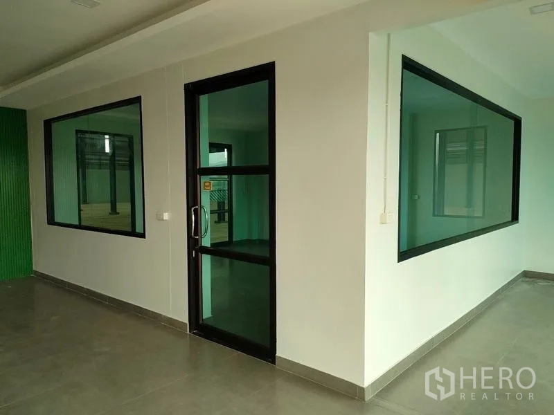 Factory for rent in Ban Phaeo, Samut Sakhon - Ground-floor corridor with glass door and large internal viewing windows.