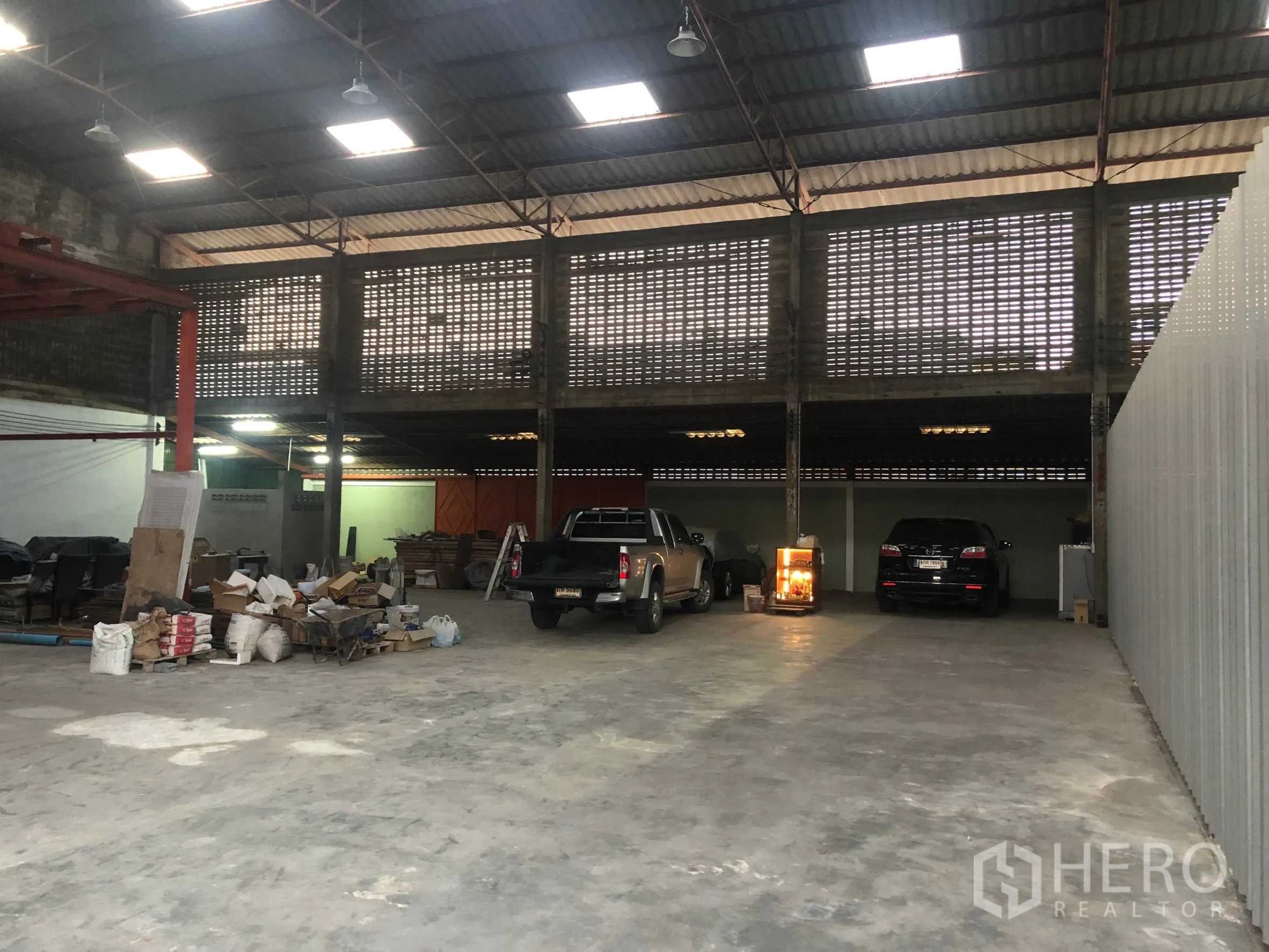Warehouse for rent in Min Buri, Bangkok - Spacious warehouse interior with high steel roof, skylights, ventilated block walls and concrete floor with truck parking.