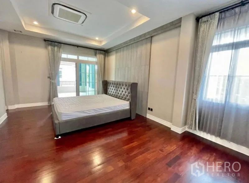 独立式住宅 出租在Bang Phli, Samut Prakan - 宽敞主卧，阶梯天花、木地板、大窗与阳台门。