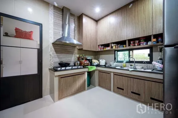 Detached House for sale in Prawet, Bangkok - Fitted kitchen with wood cabinetry, gas cooktop, stainless hood and window over sink.