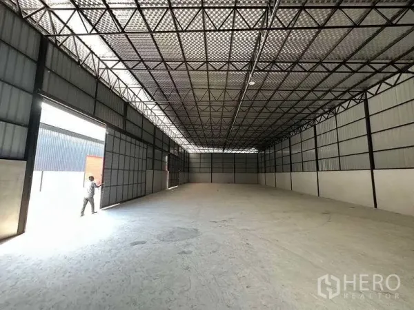 Warehouse for rent in Khlong Sam Wa, Bangkok - Open-plan warehouse interior featuring a high steel truss roof with daylight panels and a smooth concrete floor.