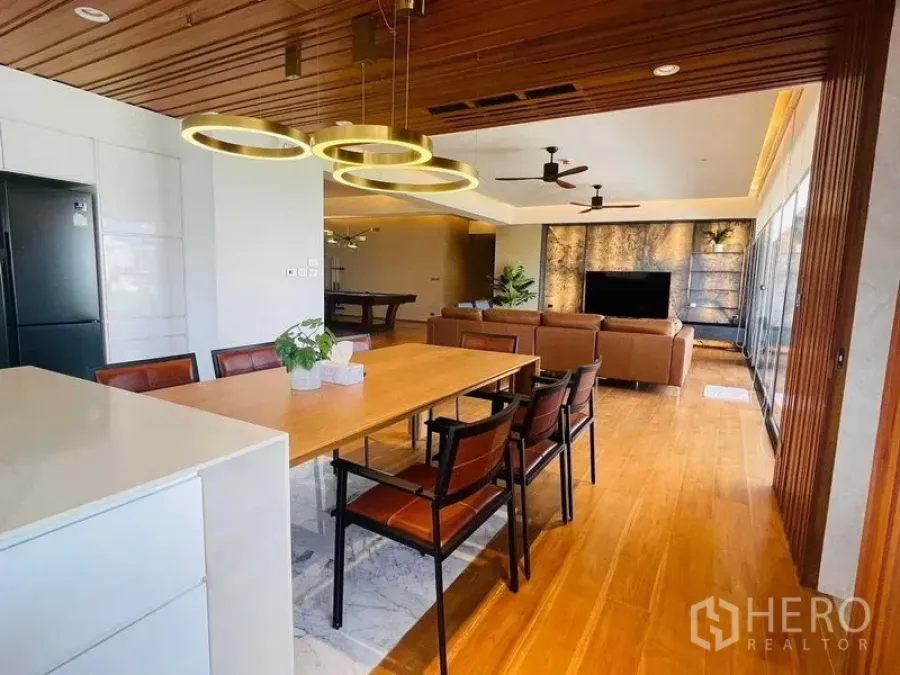 Condominium for rent or sale in Watthana, Bangkok - Open-plan kitchen and dining connected to the lounge with wood floors and modern lighting.