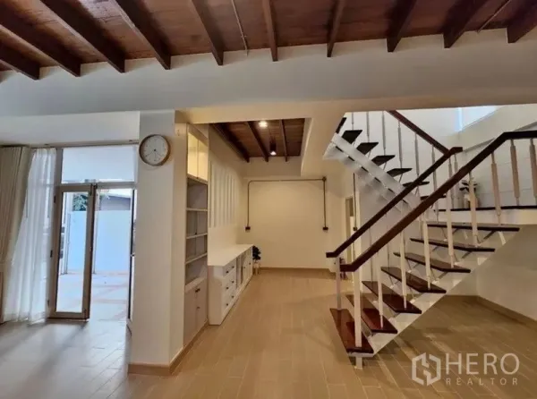 Townhouse for sale - Open-plan hallway with wooden staircase, exposed ceiling and built-in storage.