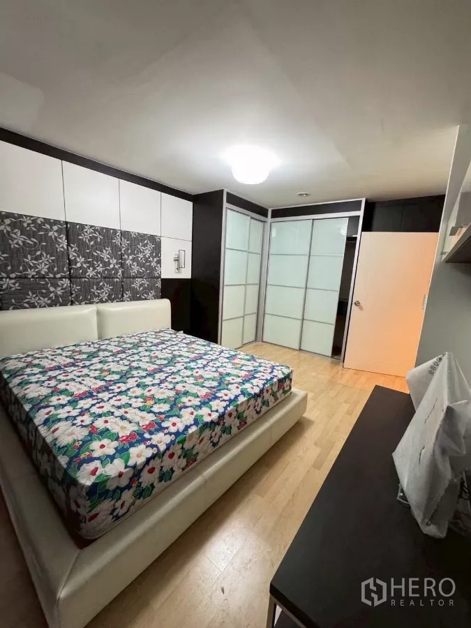 Townhouse for rent in Suan Luang, Bangkok - Second bedroom with king bed, decorative wall panels and sliding wardrobes.