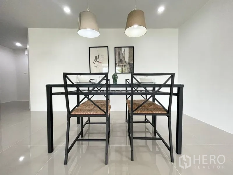Condominium for rent in Khlong Toei, Bangkok - Dining area with glass-top table, four chairs, and pendant lights.