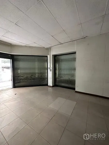 Shophouse for rent in Bang Na, Bangkok - Corner storefront area with large display windows and metal roller shutters.