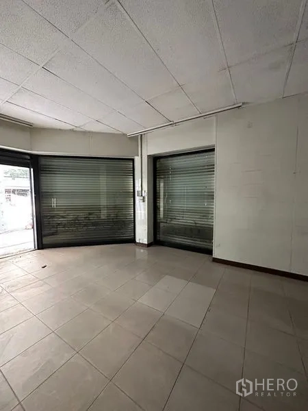 Shophouse for rent in Bang Na, Bangkok - Corner storefront area with large display windows and metal roller shutters.