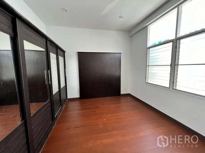Home Office for rent in Watthana, Bangkok - Bedroom with built-in dark wood wardrobes and large windows.