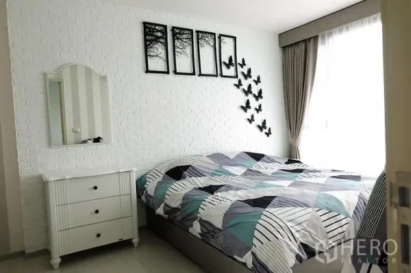 Condominium for rent in Khlong Toei, Bangkok - Cozy bedroom with white brick accent wall, butterfly decor and large curtained window.