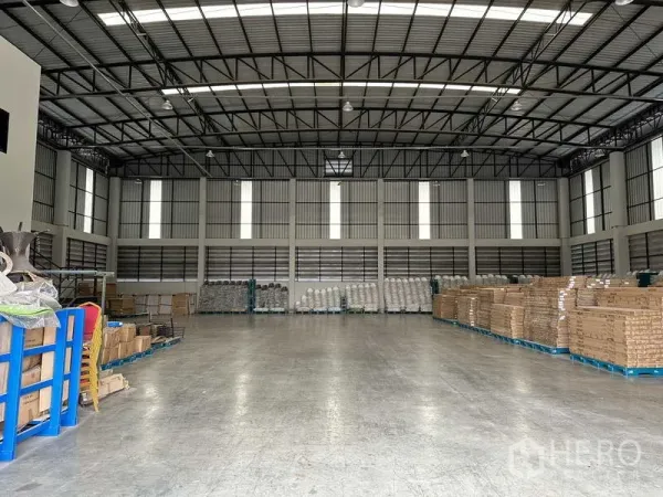 Warehouse for rent in Bang Phli, Samut Prakan - Spacious warehouse interior with high steel truss roof, skylights and polished concrete floor with pallets stored.