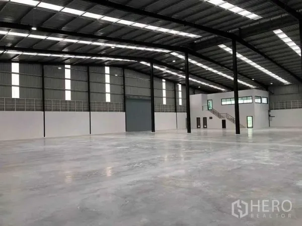 Warehouse for rent or sale in Nikhom Phatthana, Rayong - Open-plan 5,000 sqm warehouse showing high-bay ceiling, large shutter door and internal office mezzanine.