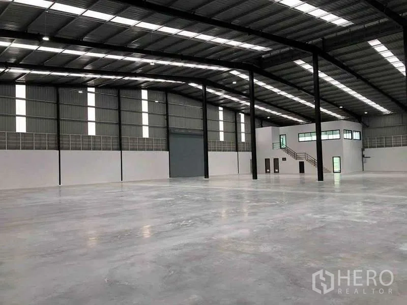 Warehouse for rent or sale in Nikhom Phatthana, Rayong - Open-plan 5,000 sqm warehouse showing high-bay ceiling, large shutter door and internal office mezzanine.