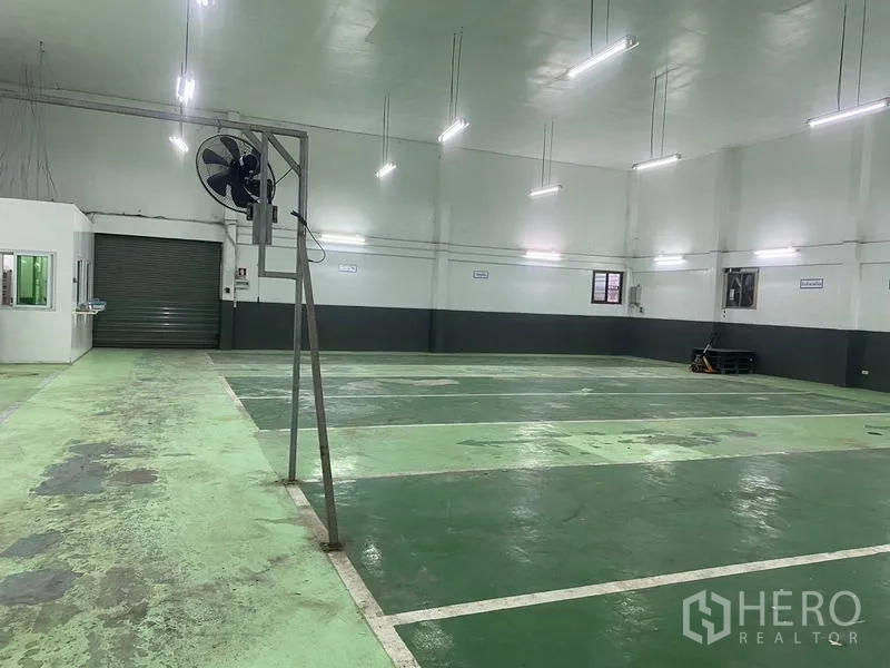 Warehouse for rent in Lam Luk Ka, Pathum Thani - Open production floor with bright lighting and roller door at the far end