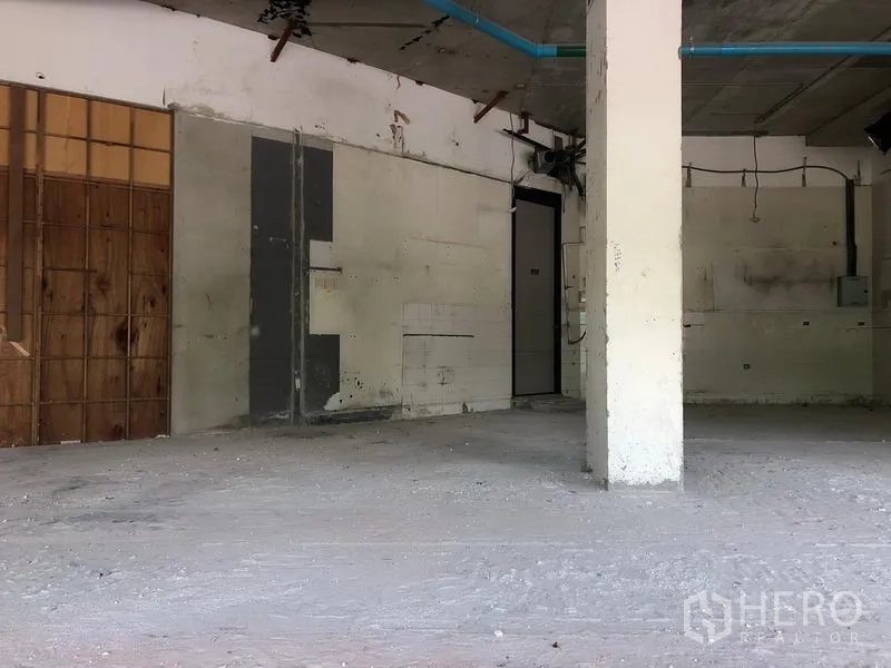 Retail Space for rent in Watthana, Bangkok - Raw retail interior with concrete floor, center column, and exposed ceiling pipes.