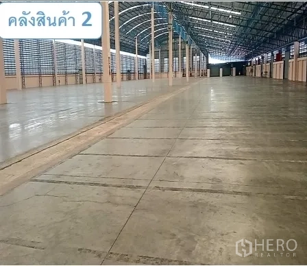 Warehouse for rent in Mueang Pathum Thani, Pathum Thani - Warehouse interior with reinforced concrete floor and steel truss roof structure.
