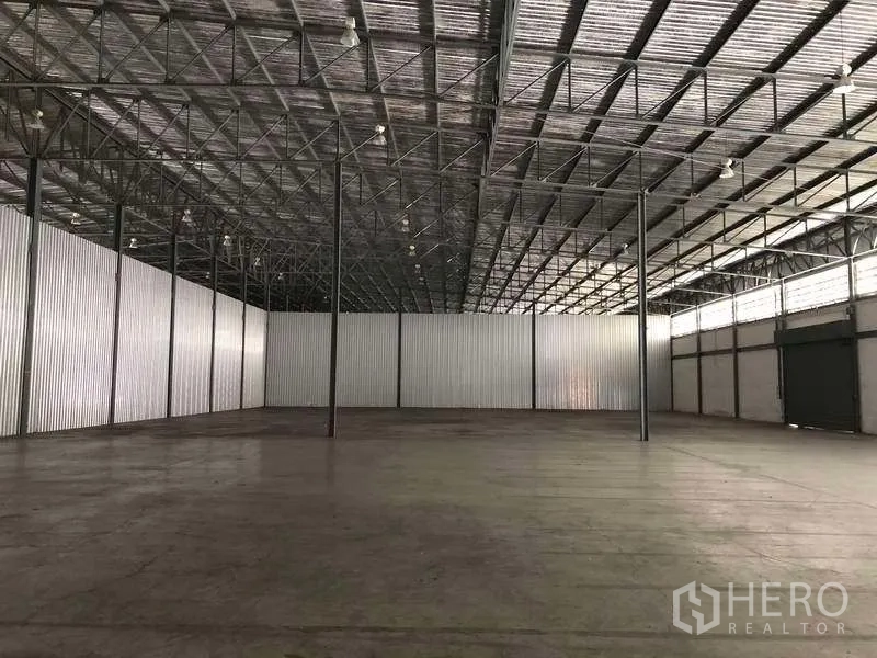 Warehouse for rent in Bang Phli, Samut Prakan - Open warehouse area with corrugated metal walls, concrete flooring and ample overhead lighting.