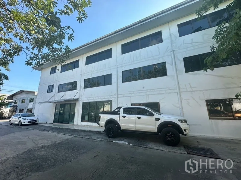 Warehouse for rent in Saphan Sung, Bangkok - Three-storey office block facade with parking in front.