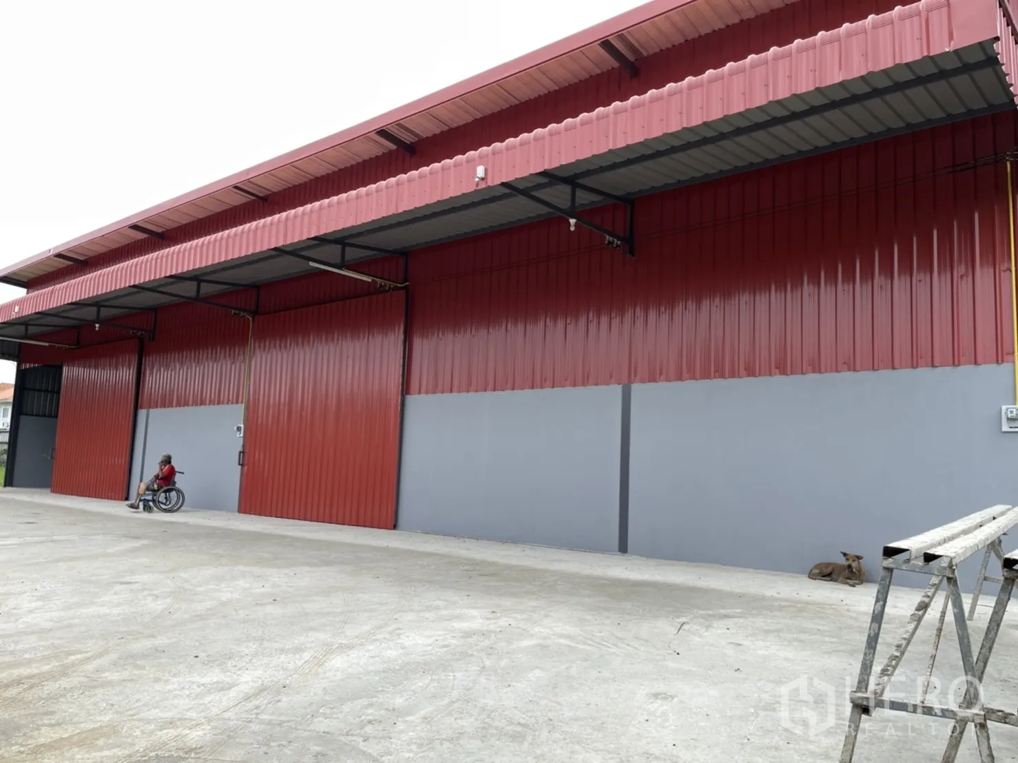 工厂 出租在Khlong Luang, Pathum Thani - 红灰配色的工厂外立面，配大尺寸推拉门与有顶装卸区。