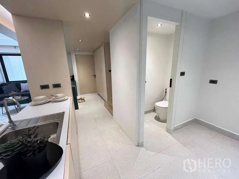 Townhouse for sale in Khlong Toei, Bangkok - Kitchen corridor with sink, storage and guest toilet near the stairs.