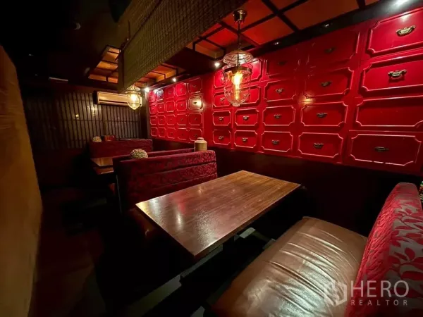 Shophouse for rent in Watthana, Bangkok - Cozy dining booths with wooden tables, a red lacquer cabinet wall and pendant lighting.