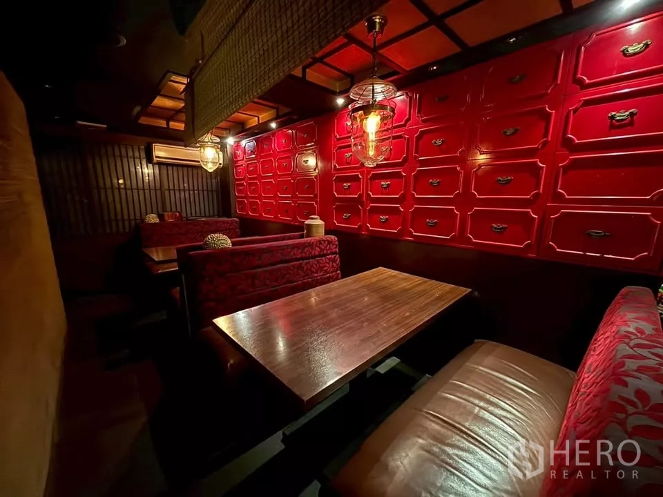 Shophouse for rent in Watthana, Bangkok - Cozy dining booths with wooden tables, a red lacquer cabinet wall and pendant lighting.