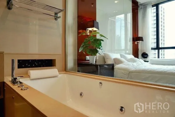 Condominium for rent in Khlong Toei, Bangkok - Modern bathroom featuring a soaking bathtub and glass partition connected to the bedroom.