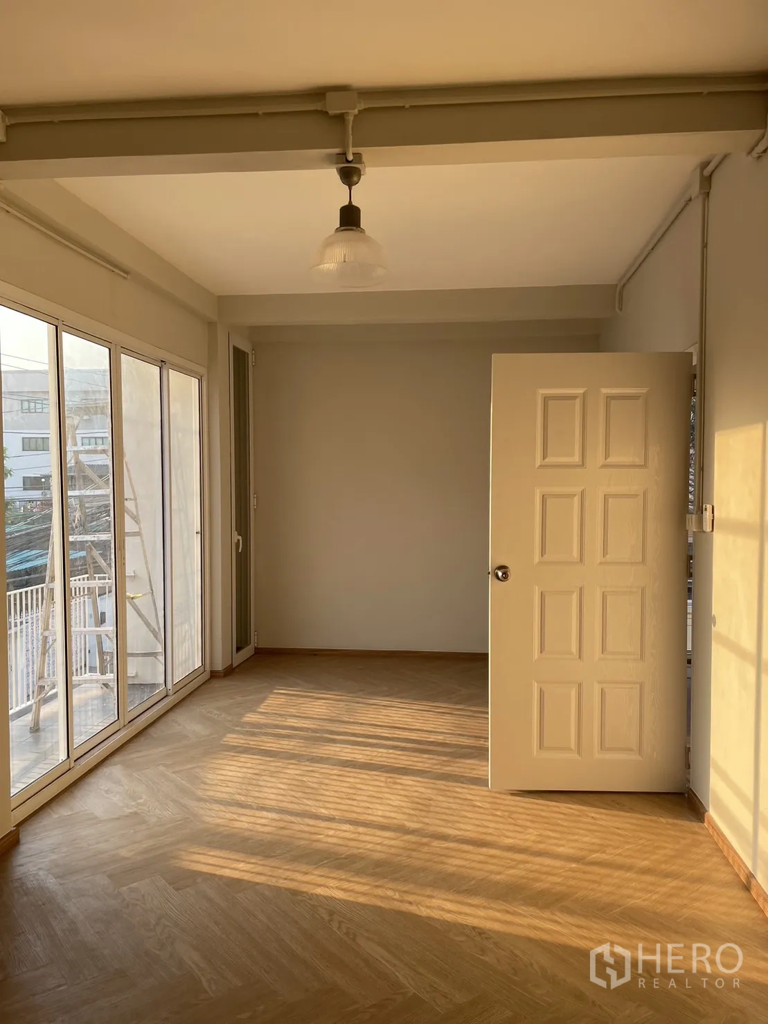 Detached House for rent or sale in Din Daeng, Bangkok - Upper bedroom with sliding doors to balcony and warm afternoon light on wood floor.