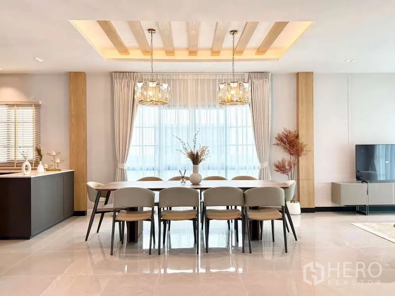 独立式住宅 出租或出售在Bang Phli, Samut Prakan - 開放式餐廳，長桌可坐十人，水晶吊燈與大面窗戶。