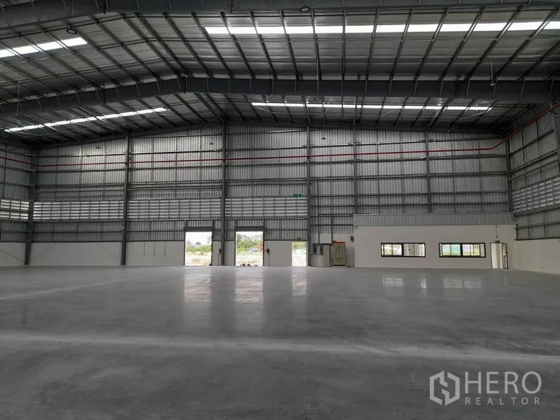 Factory for rent in Mueang Rayong, Rayong - Interior view toward large entry doors and office windows along the wall.
