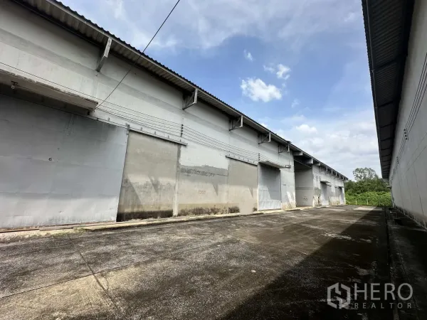 Warehouse for rent in Phra Nakhon Si Ayutthaya - Exterior corridor of multiple warehouse bays with sliding metal doors.