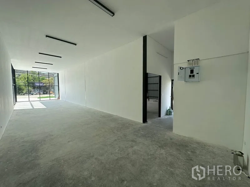 Warehouse for rent in Bang Phli, Samut Prakan - Open-plan office area with electrical panel and doorway connecting to the main warehouse.