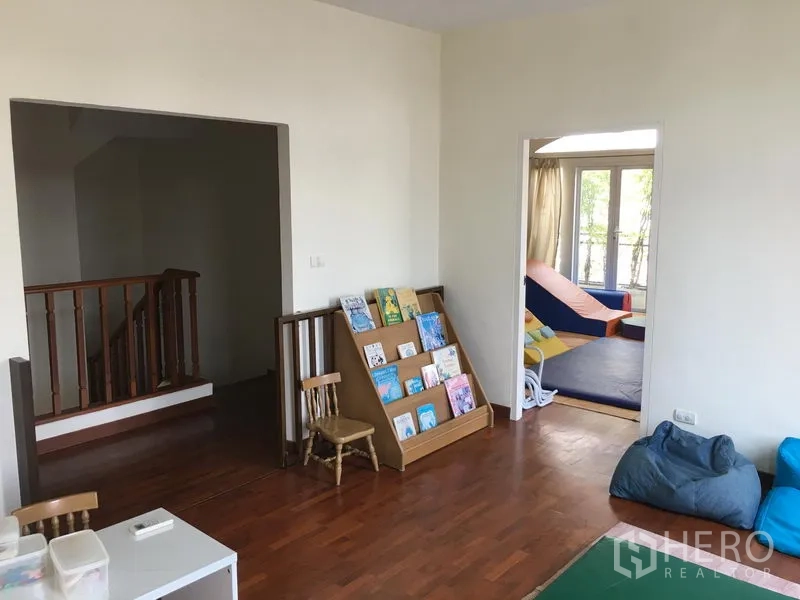 Townhouse for sale in Huai Khwang, Bangkok - Family room with wooden floor, built-in book rack and an adjoining bedroom with balcony.