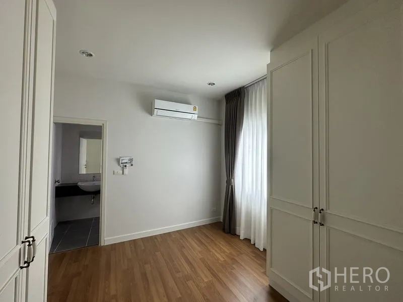 Detached House for sale in Lam Luk Ka, Pathum Thani - Bedroom with built-in wardrobe, air conditioner and ensuite entry.