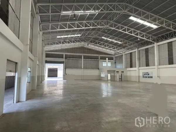 工厂 出租 - 从侧面看到的仓库空间，带天窗、装卸门及办公窗。